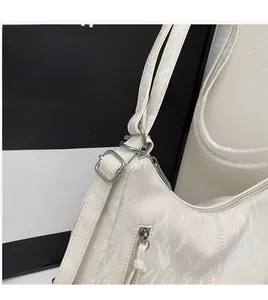 Close-up of adjustable long strap and silver hardware on a cream wrinkled leather bag