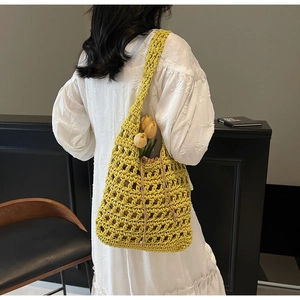 Detalle del bolso de hombro trenzado amarillo con diseño de malla y forro de cordón