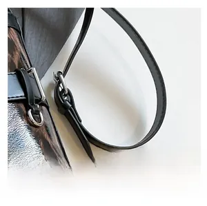 Detail of adjustable black leather strap with silver metal buckle on leopard print bag
