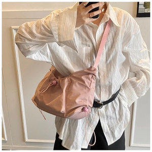 Detail of pink nylon crossbody bag featuring pleated drawstring design and adjustable strap