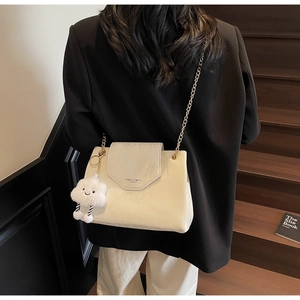 Detail of off-white leather shoulder bag with golden chain and plush cloud charm accessory