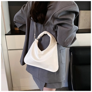 Detail showing white geometric triangle bag with silver chain strap and metal ball decoration