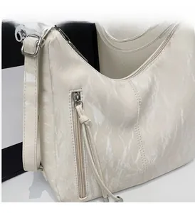 Close-up of cream white pleated leather bag showing smooth metal zipper and texture