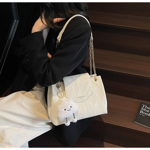Detail of off-white pleated leather shoulder bag with chain strap and plush cloud charm