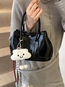 Chic black patent leather handbag with fluffy white cloud charm on neutral background