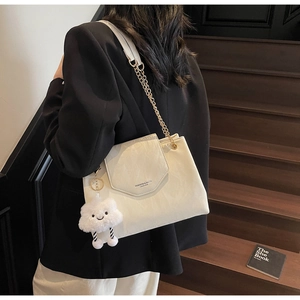 Detail of cream white shoulder bag with gold chain strap and plush cloud charm
