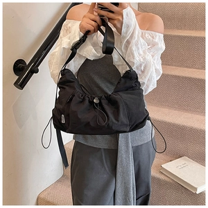 Detailed macro view of black nylon dumpling bag with adjustable strap and side label
