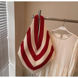 Close-up of red and beige V-stripe crochet tote bag hanging with a white shirt