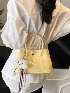 Pale yellow patent leather tote bag with a cute cloud charm shown on a female model