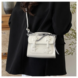 Detail of white messenger bag with star patch, happiness lettering and lace bow decoration