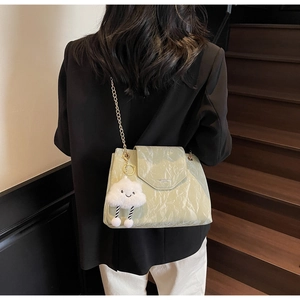 Detail of light green glossy pleated bag with golden chain strap and cloud charm