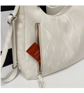 Detail showing the side zipper pocket on a beige pleated tote bag with smooth texture
