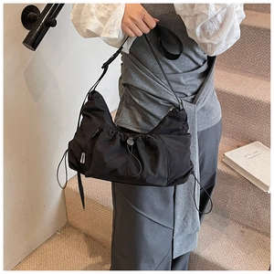 Detail of black nylon drawstring tote with ruched texture and adjustable shoulder strap