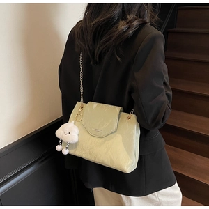 Detail of light green pleated leather bag featuring metal chain strap and white cloud charm
