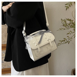 Detail of white messenger bag with 3D star patches and a black checkered ribbon bow