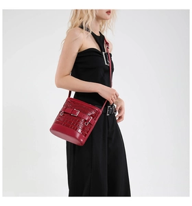 Detail of dark red crocodile embossed bucket bag with stylish metal buckle and thin strap