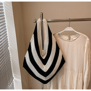 Detail of black and white striped knitted hobo bag showing texture on a hanger