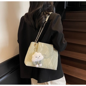 Detail of light green marble textured handbag with gold chain and plush cloud charm