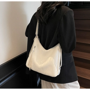Fashionable cream white hobo bag with fringe detail and silver zipper shown on shoulder