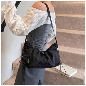 Detail view of a black drawstring nylon tote bag with drawstring folds and label