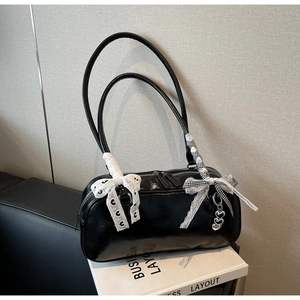Detail of black patent leather bag with lace bow and silver heart chain charm
