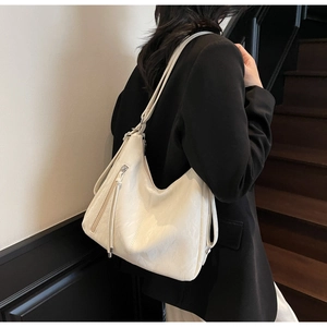 Chic cream oversized shoulder bag with soft pleated leather and tassel detail on model