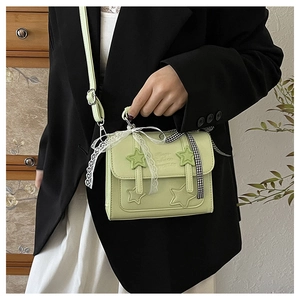 Detail of mint green star crossbody bag with decorative lace bow and leather strap