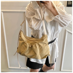 Detailed view of beige nylon crossbody tote bag with adjustable strap on a model
