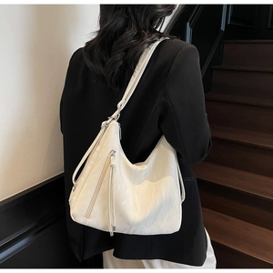 Detail view of the cream white pleated PU leather hobo bag with long zipper tassels