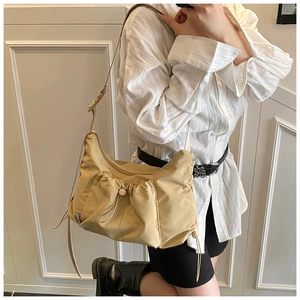 Detail of khaki nylon tote bag featuring front drawstring pocket and adjustable strap