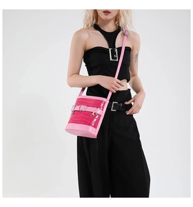 Sac seau rose à texture crocodile avec boucle en métal porté à l'épaule du modèle