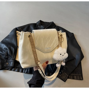 Close-up of white marble pattern handbag with gold chain strap and plush cloud charm