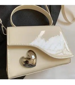 Dettaglio della borsa a spalla in pelle verniciata bianca con grande fibbia a cuore in argento
