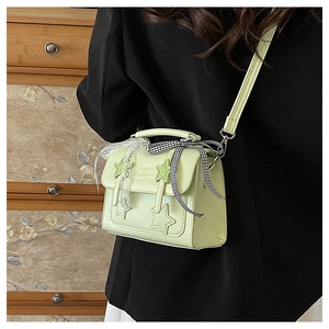 Close-up of light green messenger bag with star patches and white lace details