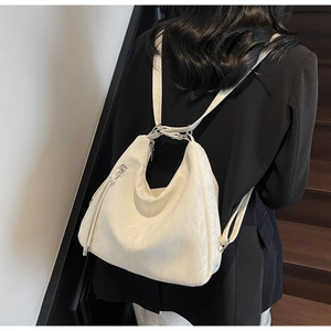 Detail of soft beige leather backpack with silver hardware and stylish tassel accent