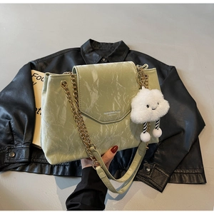 Close-up of green marble textured handbag with gold chain and plush cloud charm