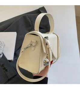 Dettaglio di una mini borsa in vernice bianco crema con finitura lucida e fibbia argento
