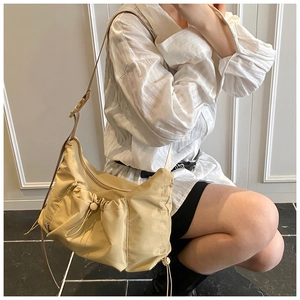 Detail of beige nylon tote bag with pleated drawstring pocket and adjustable strap