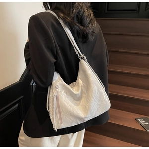 Detail of white pleated hobo bag with tassel zipper and adjustable strap in use