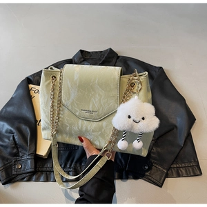 Detail of light green marble texture bag with gold chain and white cloud charm