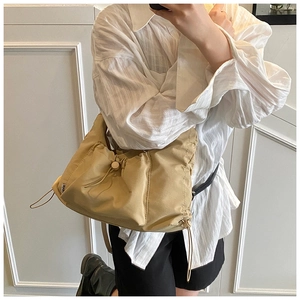 Close-up of khaki pleated nylon tote bag featuring a minimalist white brand label