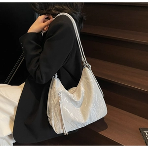 Detail of pearl white hobo bag with pleated texture and side zipper on wooden stairs