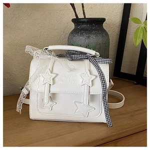 Close-up of white star applique messenger bag with lace bow and checkered ribbon details