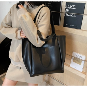 Detailed view of the large black minimalist tote bag with a functional front pocket