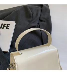 Dettaglio borsa a mano bianca in vernice con fibbie argentate e manico elegante
