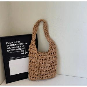 Detalle del bolso tipo saco de tejido beige con patrón calado y forro de cordón