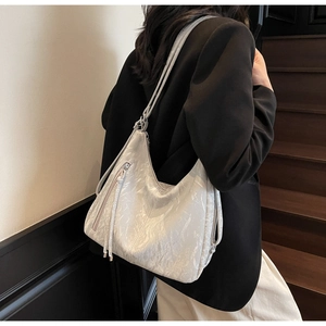 Detail of silver metallic hobo bag featuring crinkled leather texture and long tassels