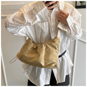 Detail of a pleated khaki nylon crossbody bag showing the soft fabric texture and side label