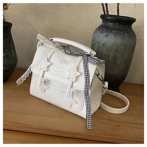 Close-up of white star crossbody bag with star patches and decorative lace ribbons