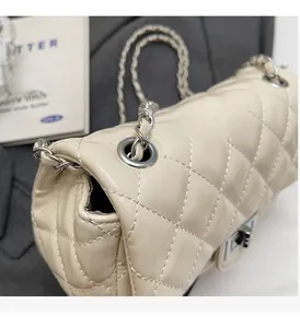 Close-up of beige quilted leather bag with silver triangular lock and metal chain